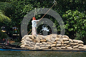 Allepey, Kerala, India Ã¢â¬â March 31, 2015: Indian man transport dwell with rice for boats. backwaters canoe in state